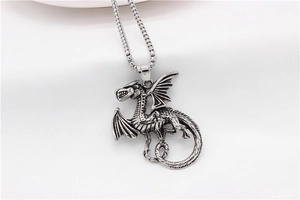 Detailed close-up of a vintage silver dragon pendant necklace with a box chain