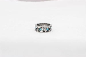 Detail of vintage steel ring featuring hollowed Celtic knot patterns and turquoise stones