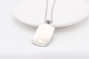 Close-up of minimalist silver stainless steel military dog tag pendant on round tray