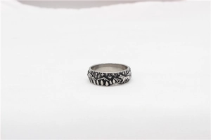 Detail of vintage wolf relief on silver steel ring featuring forest and stars