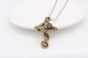 Macro detail of gothic retro dragon wrapped around a cross pendant with skull emblem