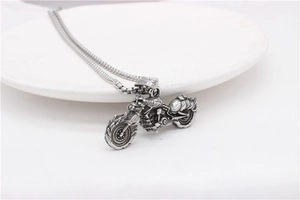 Detail view of vintage motorcycle pendant and square link chain on white plate