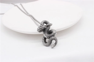 Detailed view of vintage silver snake pendant with intricate engraved scales on white plate
