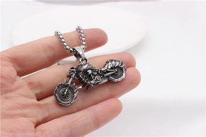Detail of vintage stainless steel motorcycle pendant with flame wheel and engine texture