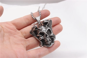 Detailed close-up of vintage steel skull pendant with coiled king cobra snakes and square chain