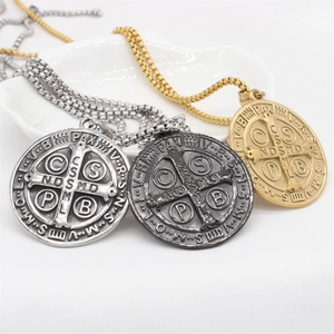 Détails macro des pendentifs religieux Saint Benoît en finitions or, argent et noir