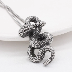 Retro stainless steel snake pendant necklace with detailed scales on white ceramic background