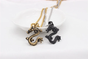 Macro shot of 3D dragon pendants in vintage gold and matte black on a white ceramic dish
