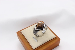 Macro shot of men's vintage steel ring featuring square tiger eye stone and carvings