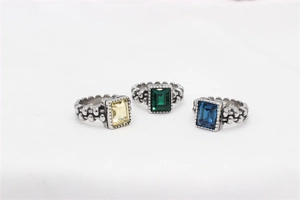 Close-up of vintage silver rings with emerald-cut yellow, green and blue gemstones