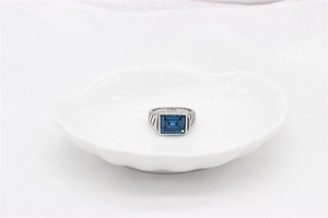 Detalle de anillo para hombre en acero plata con gema azul y textura de cable trenzado