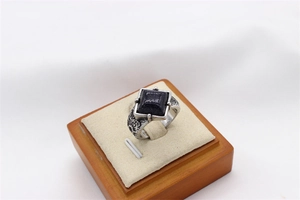 Detail of vintage stainless steel ring featuring a square blue stone and ornate carvings