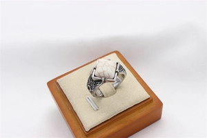 Detail of vintage steel ring with square white stone and sun engraving on wood stand