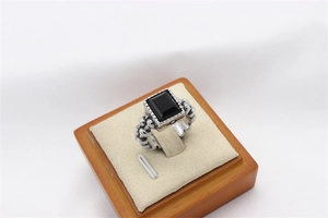Macro view of vintage silver ring featuring a rectangular black gemstone and chain texture