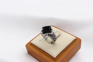 Detailed macro view of vintage silver steel ring with square black gemstone and relief texture