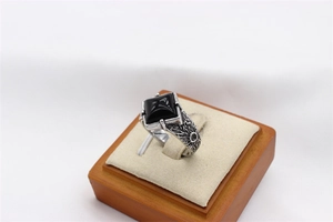 Macro detail of men's vintage stainless steel ring featuring a black gemstone and carvings