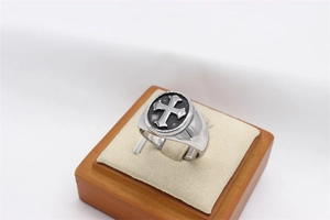 Macro detail of men's vintage steel ring featuring embossed cross and oxidized finish
