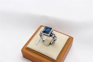 Detail view of a vintage silver ring featuring a rectangular blue gemstone and chain texture