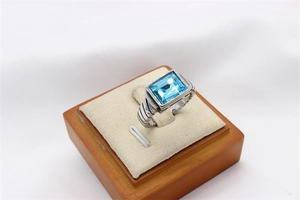 Primer plano de la gema azul rectangular y el anillo de acero con diseño de cable