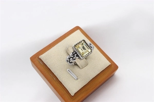 Macro shot of a vintage silver ring with a large rectangular yellow gemstone in a wooden box