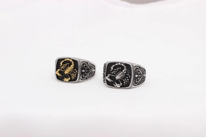 Detail of gothic stainless steel signet rings with gold and silver scorpion relief motifs