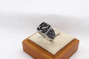 Macro detail of men's stainless steel signet ring with scorpion engraving and scroll texture