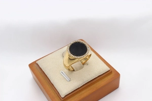 Detail of a gold titanium ring with a round black onyx center and small white crystals