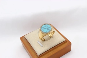 Macro detail of gold signet ring with round turquoise center and crystal halo decor