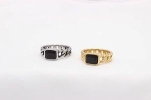 Detailed view of Cuban link chain rings with rectangular black gemstone in gold and silver