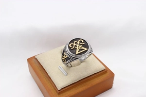 Macro view of vintage Viking signet ring with gold mystic totem on beige wooden stand