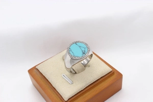 Macro shot of silver titanium ring with blue gemstone and zircon halo on wood box