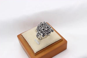 Macro detail of retro silver tribal mask ring with oxidized embossed finish