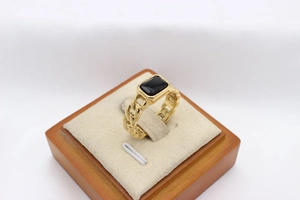 Macro shot of gold Cuban chain ring featuring a rectangular black stone inlay