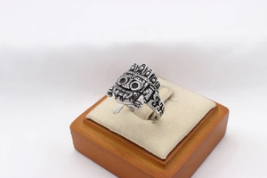 Detailed close-up of retro silver alien robot ring with intricate tribal carvings