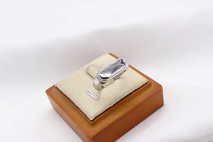 Gros plan d'une bague argentée au design fluide irrégulier sur un support en bois massif