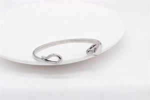 Close-up of polished silver steel snake bracelet with minimalist C-shape on white dish