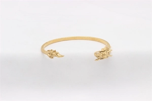 Detailaufnahme eines goldenen Drachenschuppen-Armbands mit geschnitzten Drachenköpfen