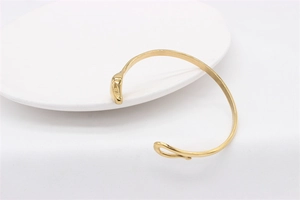 Detail of gold-plated open snake bracelet with polished finish and animal head motif
