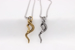 Detailed macro view of snake pendants in gold and silver showing realistic scales and texture