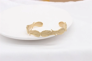 Dettaglio della trama a piuma dorata e finitura opaca sul bracciale in acciaio vintage