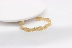 Dettaglio dell'intricata incisione a piuma e finitura dorata sul bracciale in metallo