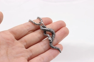 Macro detail of silver stainless steel snake pendant with textured scales and box chain