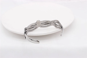 Detail of vintage silver titanium steel open cuff bracelet with hollow wave patterns