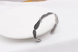 Dettaglio del motivo a piuma vintage e trama ossidata su bracciale da uomo