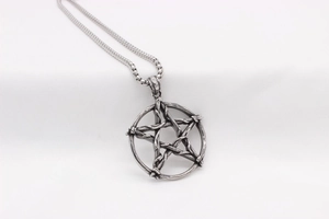 Gros plan d'un pendentif pentagramme en argent vintage avec texture tissée sur une chaîne