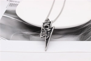 Detail of vintage lightning bolt and skull pendant on a round box chain necklace