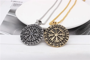 Detail of Viking Vegvisir compass pendants in gold and silver with runic engravings