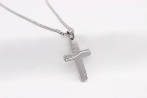 Macro shot of silver cross pendant with split texture, brushed metal, and zircon inlay