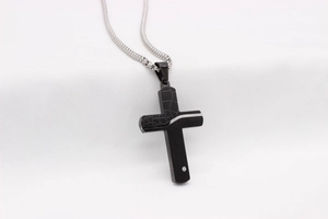 Macro detail of cross pendant featuring crackle texture, black matte finish and small zircon