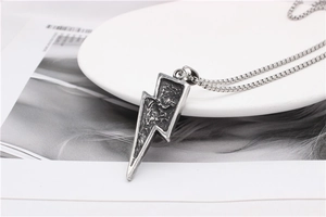 Detailed view of vintage silver lightning bolt pendant with textured finish on pearl chain